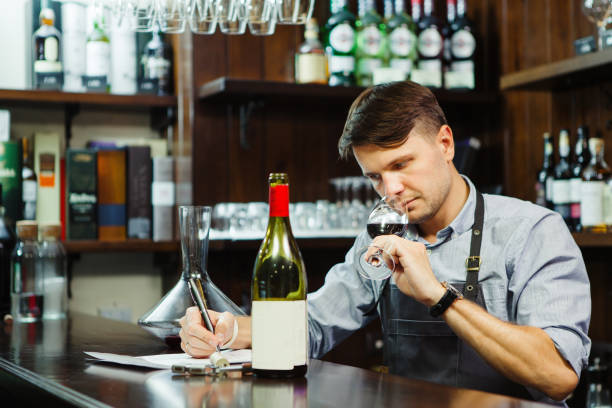 istock Male sommelier tasting red wine and making notes at bar counter 1150489544