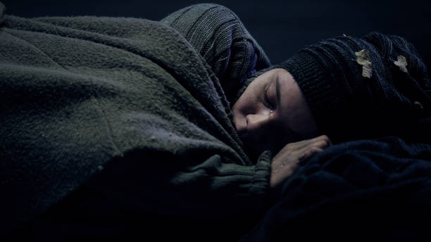 istock Crying homeless person covered by blanket sleeping on city street, problems 1150489652