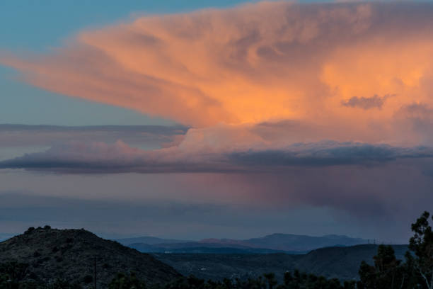 A thunderstorm is highlighted by the sun setting over the town of Joshua Tree as see from the Black Rock Campground from Joshua Tree National Park.