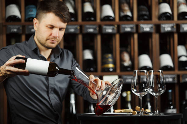 istock Serious sommelier pouring red wine in decanter 1150492373