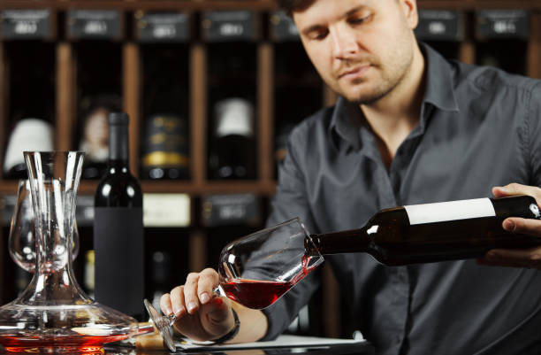 istock Sommelier pouring red wine from bottle in glass 1150493104