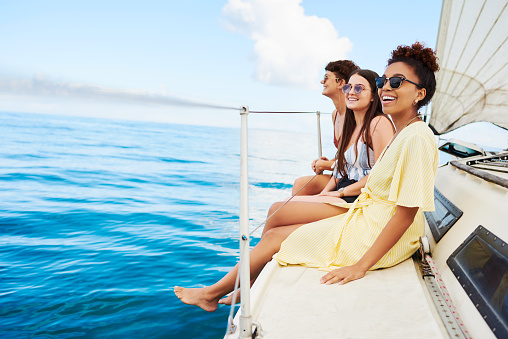 Luxury vacation lifestyle concept, group of friends diving in the water during a sailboat excursion, young people jumping inside ocean in summer vacation from a sail and having fun