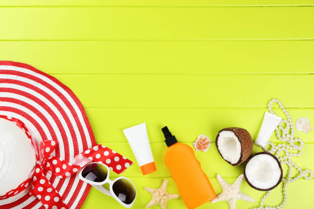 istock Sunscreen bottles with seashells, coconuts and red hat on green wooden table 1150494258