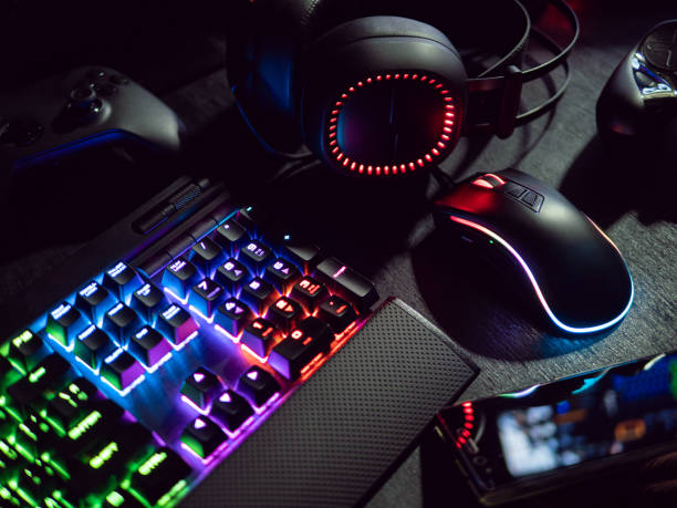gamer workspace concept, top view a gaming gear, mouse, keyboard with RGB Color, joystick, headset, webcam, VR Headset on black table background. stock photo