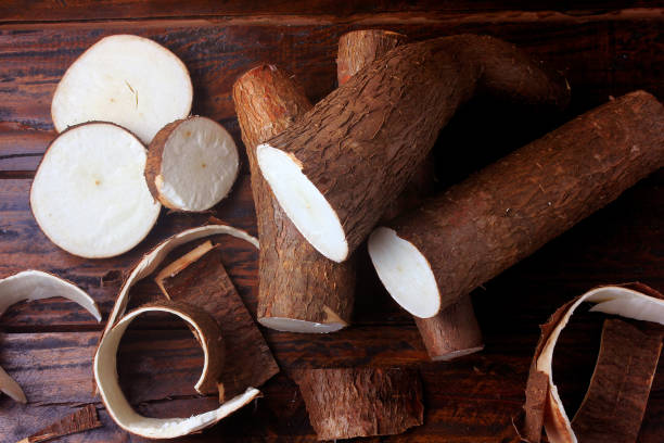 fresh cassava and peels and slices on rustic wooden table. Top view stock photo