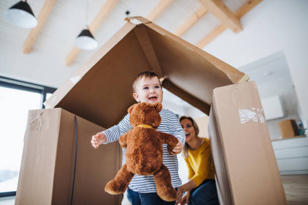 A portrait of young family with a toddler girl, moving in new home concept. A portrait of happy young family with a toddler girl, moving in new home concept. cardboard house stock pictures, royalty-free photos & images