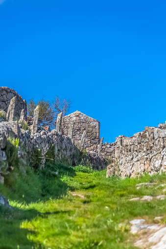 View of pedestrian path up through agricultural fields, with buildings and walls in granitic stone, built in a traditional way, in the Caramulo mountains, Portugal