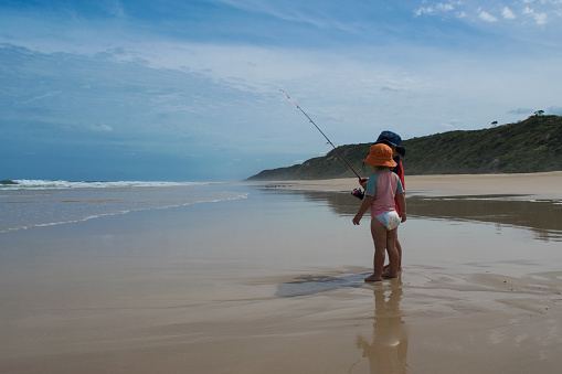 Image of two children (ages 3 and 5) fishing on a beach on Fraser Island in Australia.