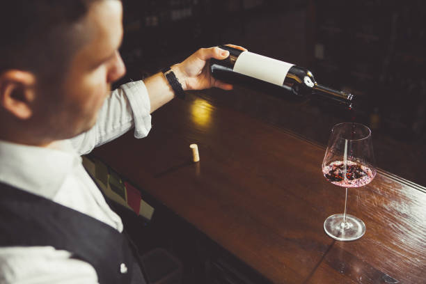 istock Closeup shot of glass with wine pouring by sommelier 1150498607