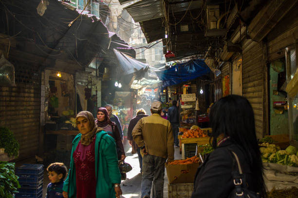 people walk through the narrow alley of a covered souk in tripoli, lebanon - tripoli imagens e fotografias de stock
