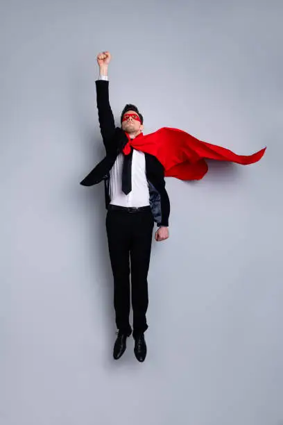 Full length body size photo jumping high he his him I save world expression costume flight up fist raised superman pose mood wear formal wear white shirt suit jacket tie isolated grey background.
