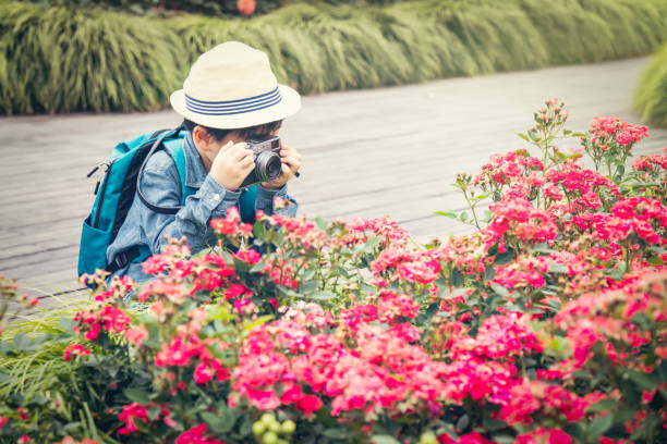 A cute boy photographer is capturing spring flowers in a park