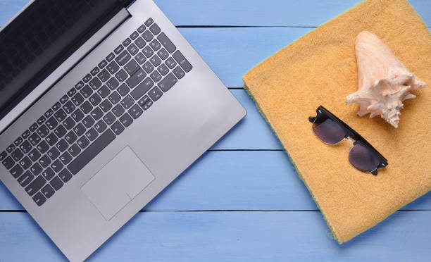 istock Online work at a beach resort. Laptop, towel, sunglasses, shell, top view, flat lay 1150506798