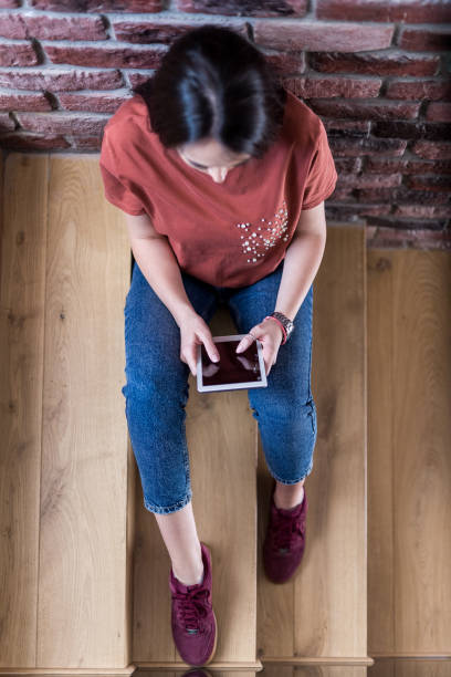 istock High angle view of young woman using blank screen digital tablet while sitting on stairs in office building. 1150507826
