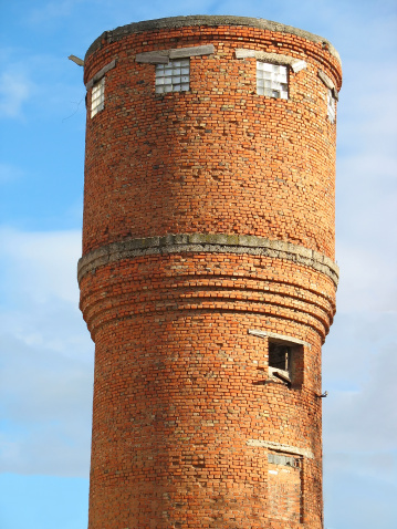 old red brick water tower over blue sky background