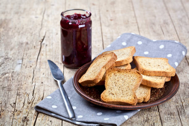 Toasted cereal bread slices on grey plate and jar with homemade cherry jam stock photo