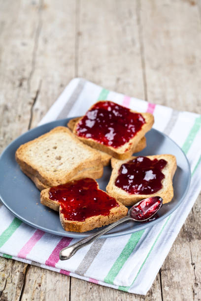 istock Fresh toasted cereal bread slices with homemade cherry jam and spoon on ceramic plate. 1150509612