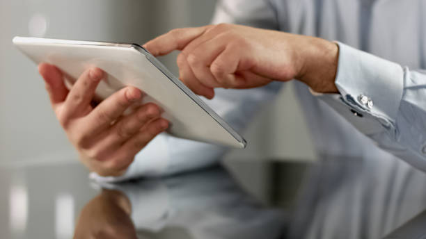 istock Businessman hands scrolling news application on tablet, touchscreen device 1150511953