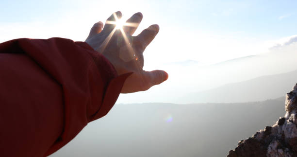 istock Hand reaches out towards the sun and mountains 1150512087