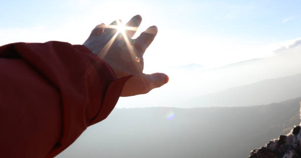 istock Hand reaches out towards the sun and mountains 1150512102