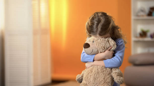 Shy curly girl hiding face behind favorite teddy bear, childhood psychology Shy curly girl hiding face behind favorite teddy bear, childhood psychology shy stock pictures, royalty-free photos & images