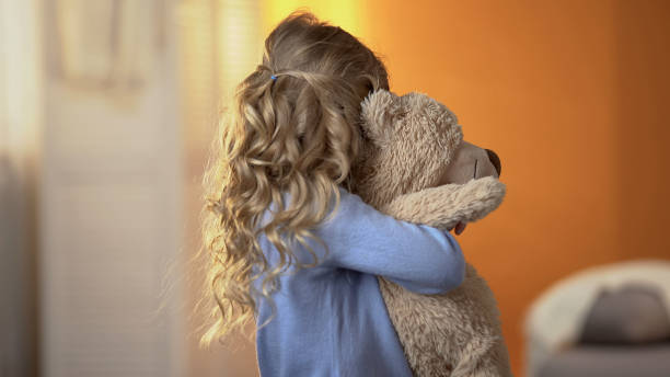 niña ofendida escondida de la cámara, impacto de las peleas parentales en el niño, problema - muñeco de peluche fotografías e imágenes de stock