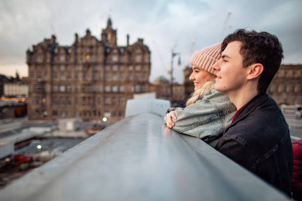 Couple Admiring the View in Edinburgh Young couple standing on the top of a rooftop admiring the beautiful cityscape of Edinburgh. edinburgh scotland photos stock pictures, royalty-free photos & images