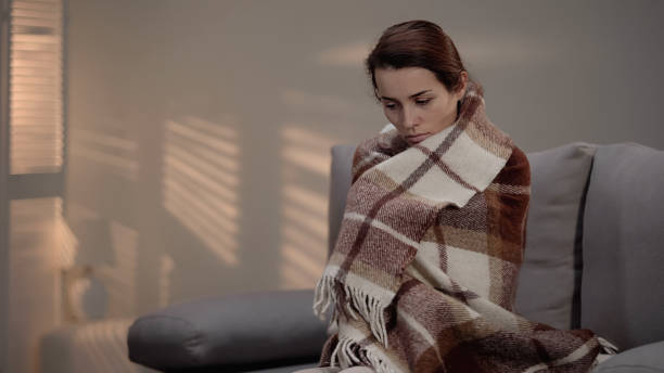 istock Lonely depressed female sitting on couch, covered with plaid, unemployment 1150512863