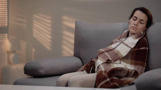 istock Lonely young depressed female sleeping on couch, covered with plaid, despair 1150512905