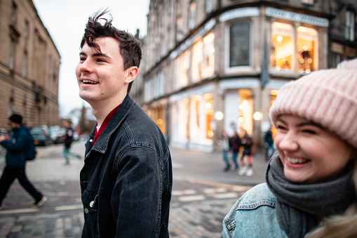 Close-up of a young couple walking through the streets of Edinburgh. They're laughing and smiling while exploring.