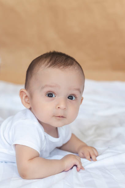 istock 6-8 month old baby boy lying playfully in bed 1150514145