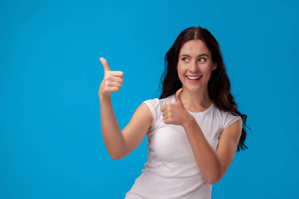 istock Smiling woman giving thumbs up on blue background 1150517883
