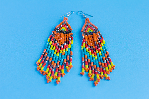 large earrings made of multi-colored beads and bugle beads, boho style, on a blue background