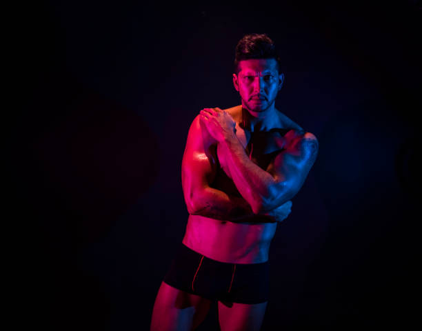 istock Handsome man in front of black background with red and blue lighting 1150523251