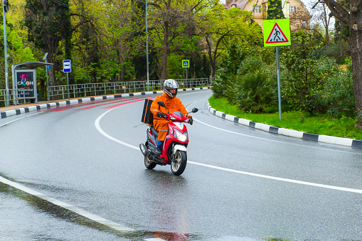 SOCHI,RUSSIA, 21 APRIL 2019 - delivery of consignments on motorbike, motorcyclist rides with delivery in the large yellow box on street