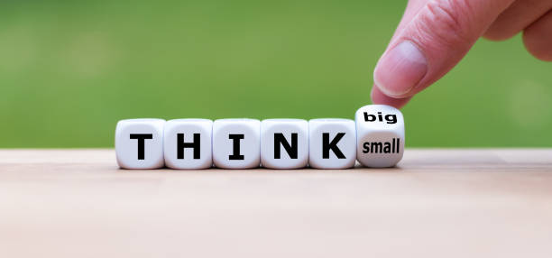la mano gira un dado e cambia l'espressione "pensare in piccolo" per "pensare in grande". - large and small foto e immagini stock