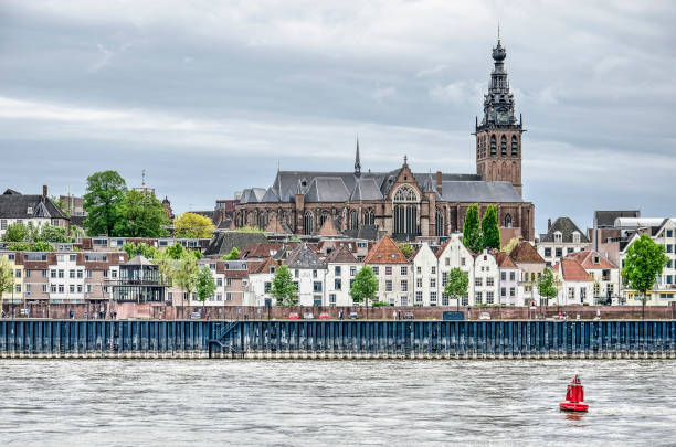 Nijmegen, The Netherlands, April 25, 2019: view of the city's waterfront and the river quay at low tide, with Saint Stephen's church towering over old and new houses