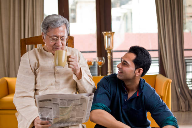 man with senior father at home - reading newspaper 30s adult imagens e fotografias de stock