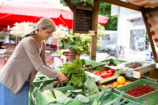 istock Farmer's Market: vendor offering organic vegetables at market stall 1150526604