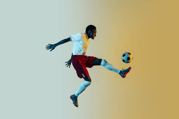 istock Male soccer player kicking ball in jump isolated on gradient background 1150526621
