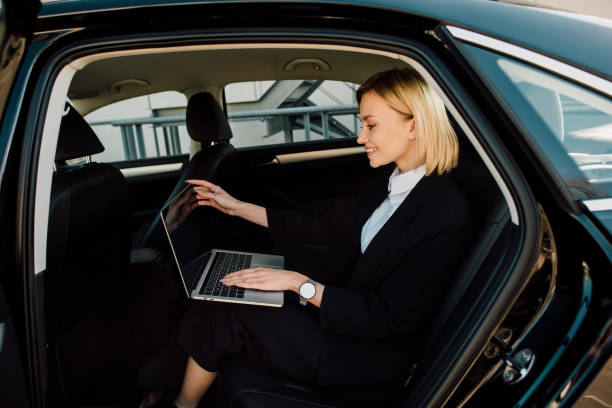 istock happy blonde young woman using laptop while sitting in car 1150526757