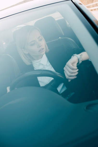 istock attractive blonde driver looking at watch while holding steering wheel 1150526805