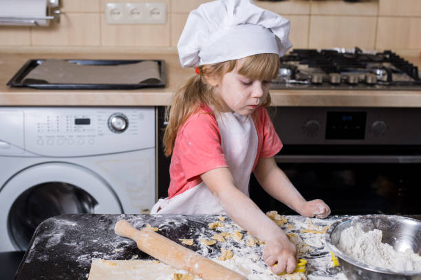 istock Little baker kid girl in chef hat at kitchen. 1150529967