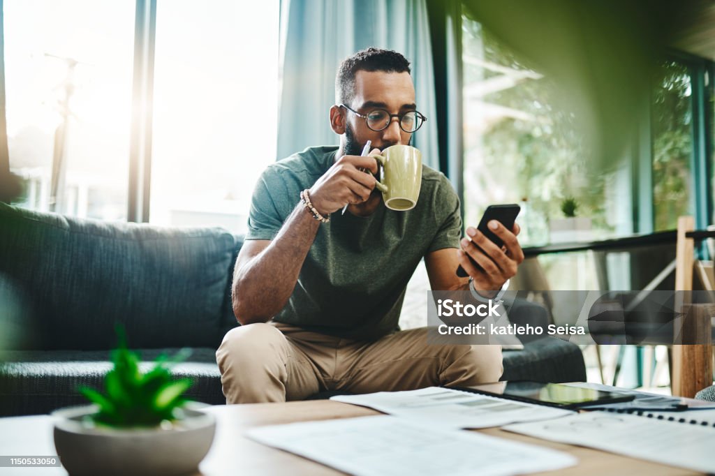 Smart apps make for smarter financial planning Shot of a young man using a smartphone while going over his finances at home Men Stock Photo