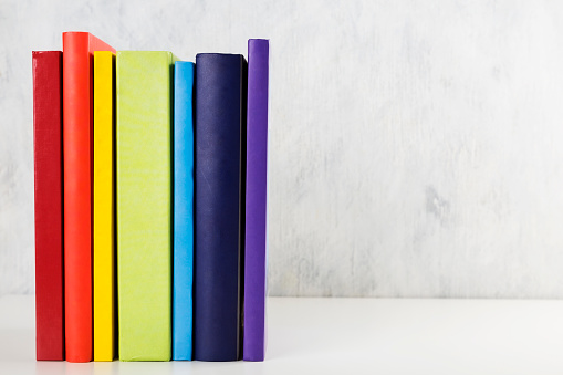 Stack of colorful rainbow books on white background. Copy space
