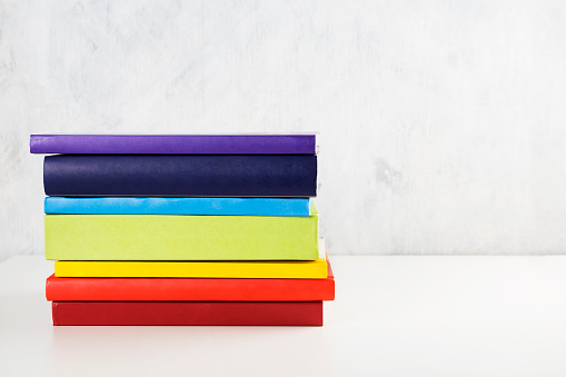 Stack of colorful rainbow books on white background. Copy space