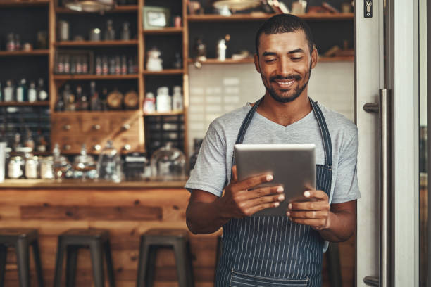 istock Young male cafe owner looking at digital tablet 1150533428