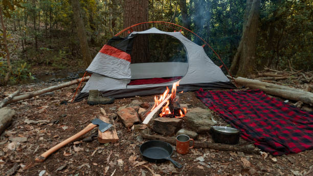 Camping tent in the Blue Ridge Mountains in Asheville, North Carolina. Outdoor lifestyle with axe, cast iron skillet, flannel blanket. Rustic Bushcraft Campsite. Survival shelter in the wilderness. stock photo