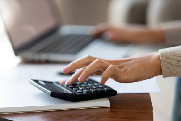 istock Cropped closeup image caucasian woman using calculator and computer 1150540128