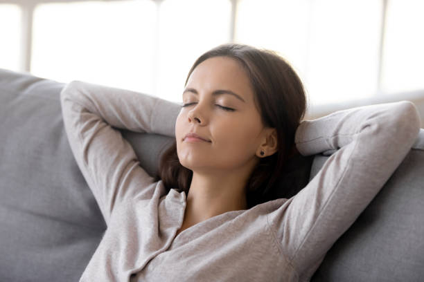 istock Calm woman putting hands behind head resting on comfortable couch 1150540144